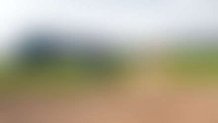 Man hitting a golf ball out of a bunker using a sand wedge, with sand flying on impact.