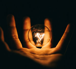Image of hand holding an illuminated lightbulb