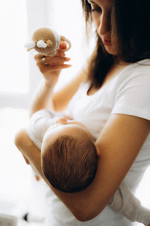 Mother holds baby, toy visible