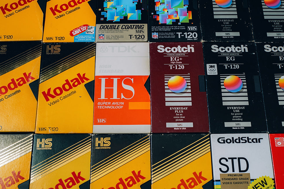 Colorful assorted VHS tape covers, featuring Kodak, Scotch, and TDK brands. Bold text, geometric designs, vintage retro feel.