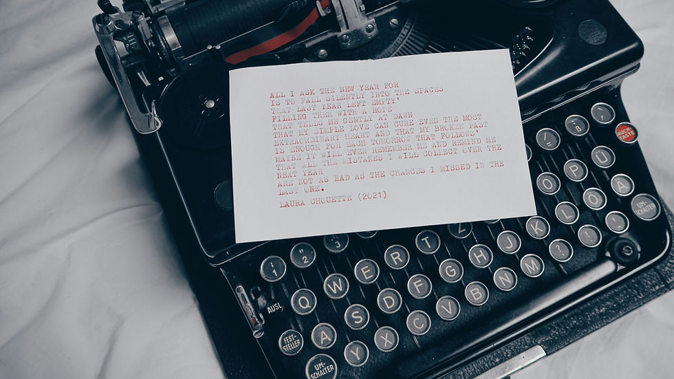 A vintage black typewriter with a typed poem on white paper resting in the roller. The poem is typed in red ink and signed "Laura Chouette (2021)." The background is soft white fabric, creating a nostalgic and literary atmosphere.