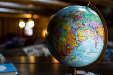 Close-up of colorful globe showing Africa and Europe. Warm, blurred indoor setting with soft lights. Peaceful and educational mood.