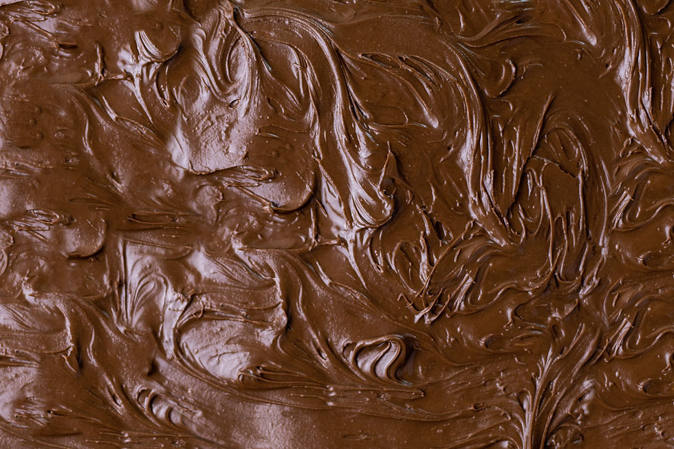 Close-up of rich brown chocolate frosting with smooth, swirling texture, creating a luscious and inviting appearance.
