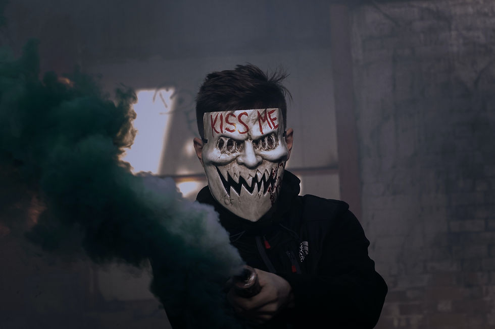 Crazy, selfish, narcissistic ex-husband wearing a menacing mask with "KISS ME" text holds a smoke flare emitting green clouds of poison in a dim, abandoned building, vindictively seeking revenge on his ex-wife.