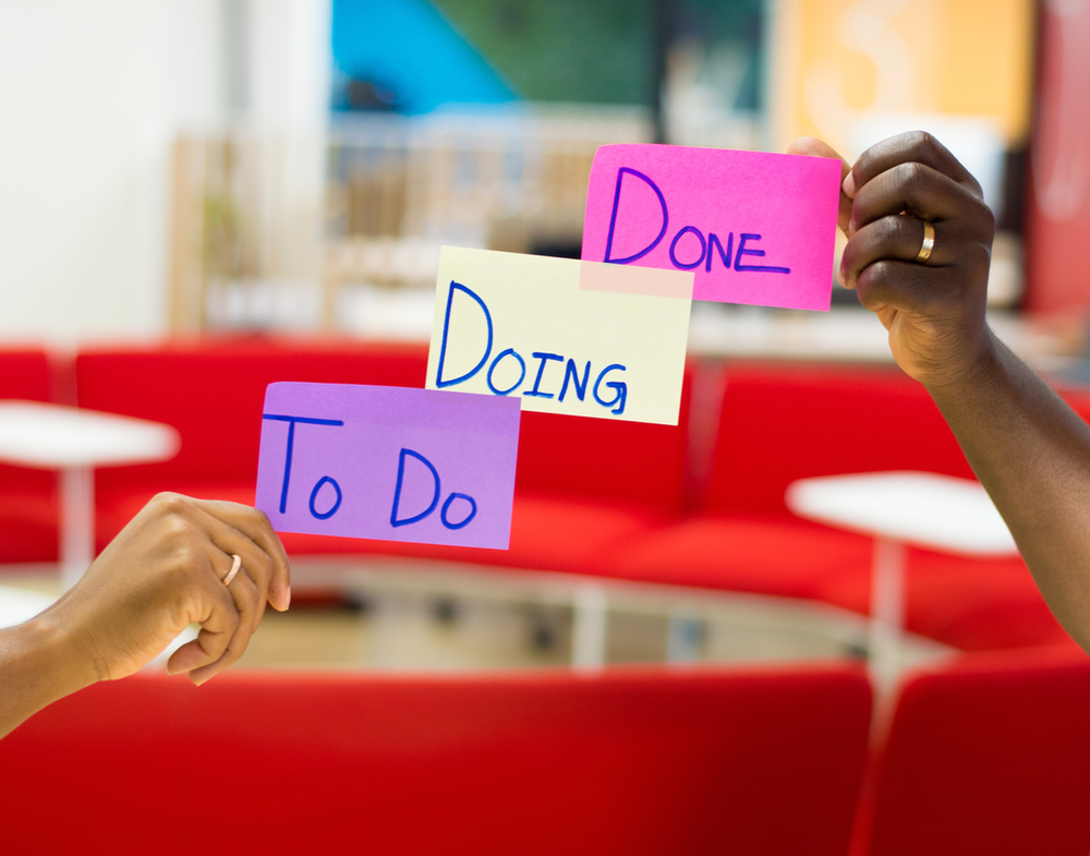 hands holding post it notes that represent some of the processes used in Agile methodology