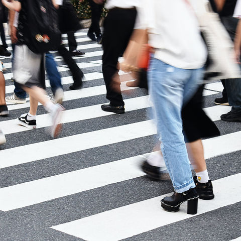 Blurred pedestrians cross a zebra crossing in the city, with black-and-white stripes and casual clothes.