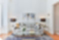 Sitting room featuring a grey neutral-colored couch, adorned with colorful and geometric patterned pillows, and complemented by abstract artwork on the wall. The interior design exudes modern and inviting ambiance.