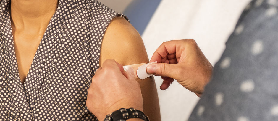 a person getting a band aid on their shoulder after a vaccine