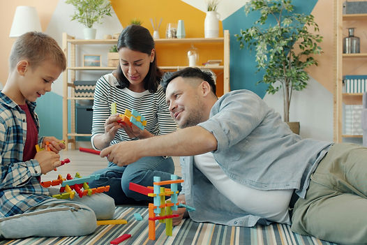 Mom, Dad and son on the living room floor playing with legos.