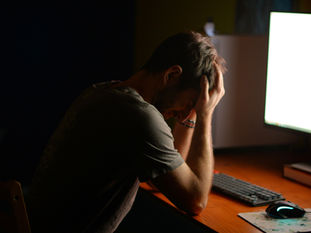 person at computer with head in their hands