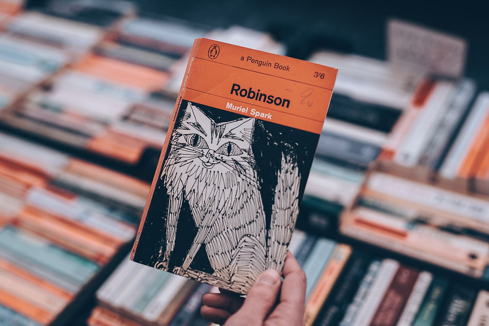Robinson by Muriel Spark paperback edition held up with a background made out of spine up books