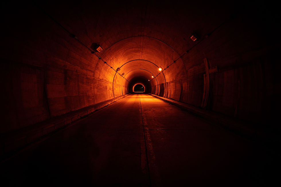 Dimly lit tunnel glowing with ominous red-orange light, creating a foreboding atmosphere of isolation, dread, and approaching danger.