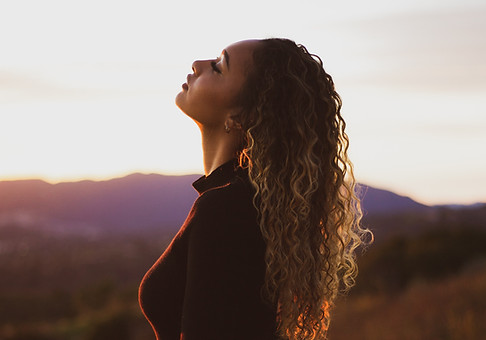 Woman standing outdoors in nature, symbolizing reflection and personal growth for women’s counseling.