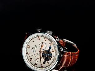 A classic mechanical wristwatch resting on a leather desk setup beside coffee, a notebook, and cufflinks, symbolizing discipline, craftsmanship, and quiet refinement.