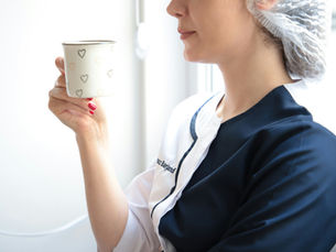 A healthcare worker holding a cup, standing tall, bearing the pressure.