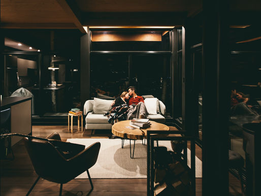 Couple cuddling on a couch in a living room at night featuring layered lighting in the apartment