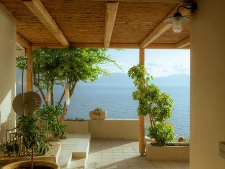 Peaceful covered terrace with plants, sunlight, and ocean view symbolizing building a resilient life after abuse, safety, restoration, and healing.