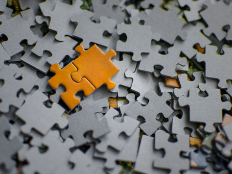 Jigsaw pieces mixed up with orange pieces connecting together in a new pattern