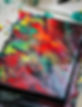 Fluid acrylic pour painting displaying organic swirling patterns of red grey yellow