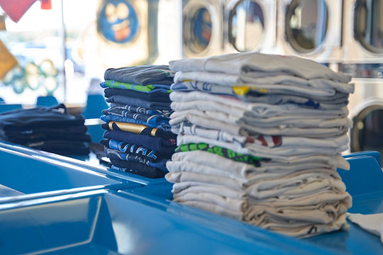 Stacks of neatly folded clothes in various colors on blue laundry baskets