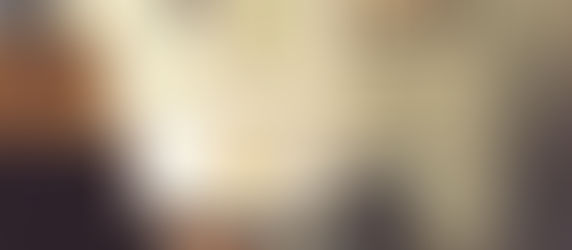 Table with colorful chairs in a cozy room, dim lighting. Art posters on the wall, one displays "Pumpkin Forever." Warm, inviting atmosphere.