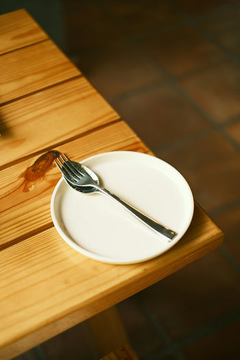 empty plate with a spoon and fork on top, on a wood table