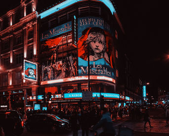 In the theatre district, a large neon banner of the musical Les Misérables lights the dark.
