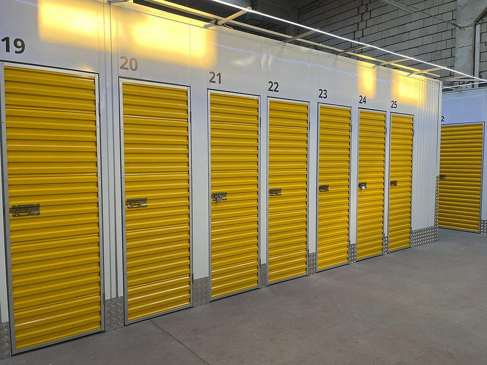 Row of yellow storage unit doors numbered 19 to 25, in a brightly lit warehouse with white walls and concrete flooring.