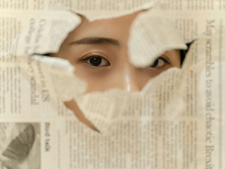 Eyes peek through a torn newspaper, with articles visible. The mood is mysterious, highlighted by the contrast of the paper's text.