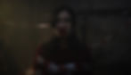 Woman wrapped in red and white caution tape, with mouth covered, in a dimly lit setting with branches. Mood is tense and mysterious.