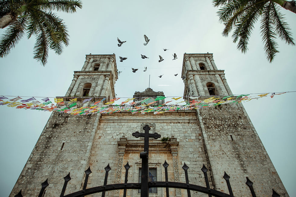 Kathedrale Iglesia de San Servacio mit Tauben im Flug, Palmwedeln und bunten Wimpeln vor hellem Himmel.