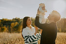 Young family at home lifting their baby in the air