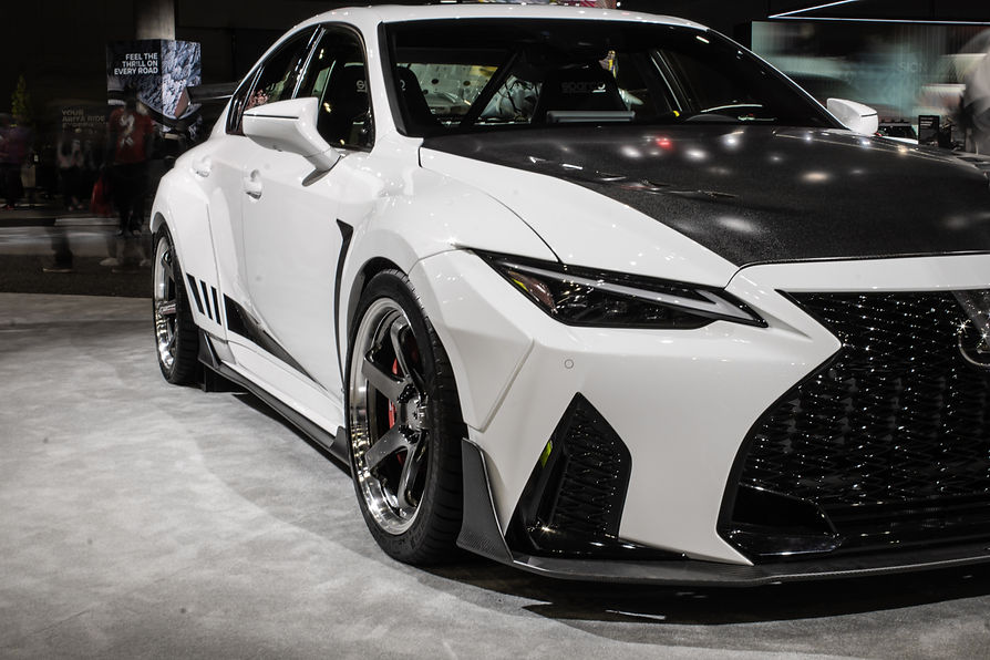 Sleek white sports car with black accents and a bold grille on display in a showroom