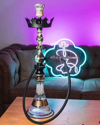 Hookah with neon light decoration against a couch, in a dimly lit room