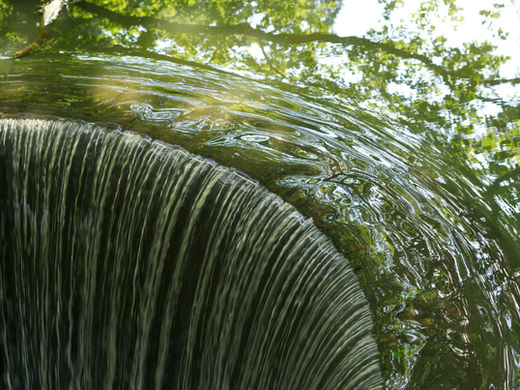 Graceful streams of water cascade over the edge at the Morton Arboretum waterfall, creating a serene and rhythmic display.