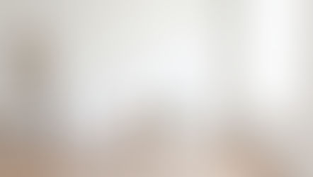 Wooden ladder, white chair, and potted plant on a light wood floor in a minimalistic, bright room with a large window on the right.