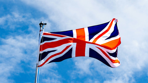 The Union Jack flag of the United Kingdom flying against a bright blue sky, representing Grid Society’s home base and national workshop reach.