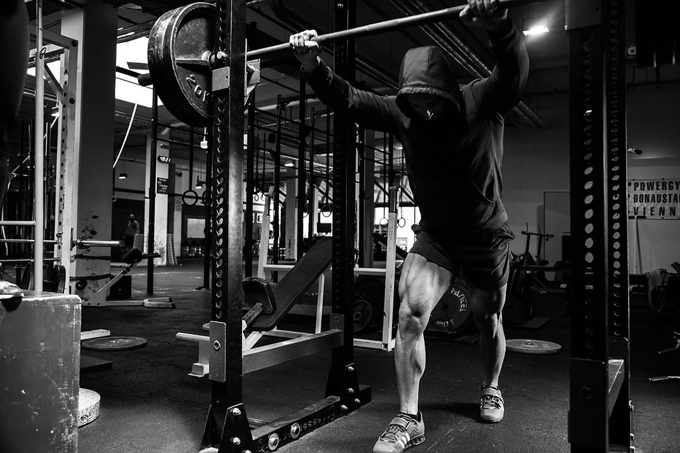 A guy about to perofrm a barbell squat as part of a lower body strength workout.