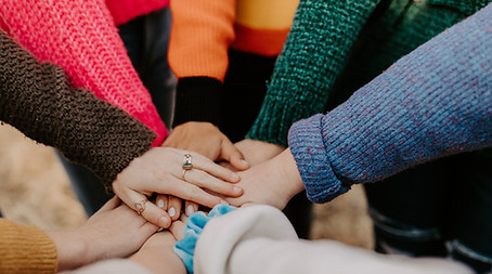 A group of people in a circle putting their hands together, representing the Californians For All's funding of Bay Valley Tech's coding bootcamps.