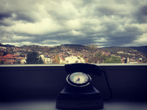 A telephone in front of a cloudy sky.