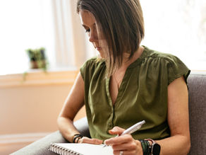 A professional woman with a notebook, pausing thoughtfully. The image symbolises reflection, resilience, and moving forward after redundancy.