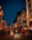 Image of a old London street at night with people walking across the street walk.