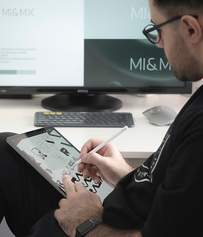 Mężczyzna pracujący jako grafik przy tablecie, tworzący projekt graficzny na ekranie.