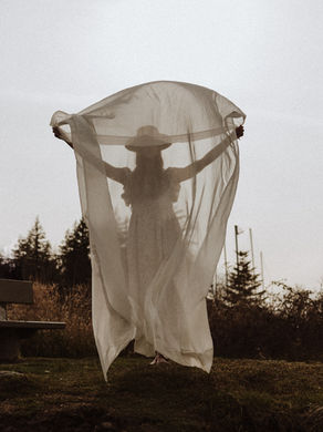 Frau mit transparentem Schal, der Wind hält diesen vor ihrem Körper