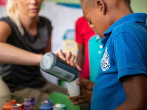 underpriveledged kids getting drink from a volunteer