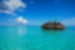 Felsen im türkisblauen Wasser und blauem Himmel