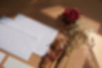 A shot of two white envelopes lying on a table next to a sprig of dried flowers (gypsophila and red roses).