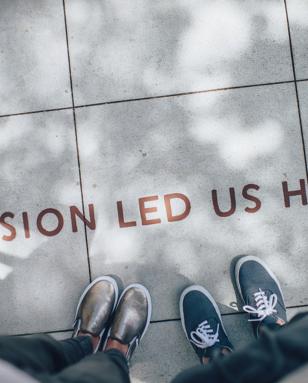 Feet standing above pavement lettering reading Passion led us here