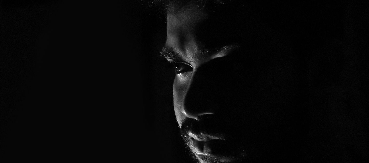 Man’s face half-lit in darkness – symbolising inner awakening, focused intensity, and the fire that rises in solitude.