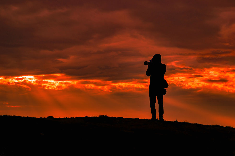 Fotoğrafçı, kıpkırmızı gökyüzünün fotoğrafını çekiyor. Fotoğrafçı siluet olarak görünüyor.
